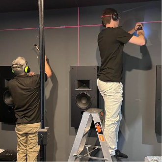 Installers positioning and aligning speakers during a real home theatre installation